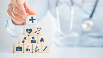 Hand arranging wood block with healthcare medical icon. Health insurance - concept.
