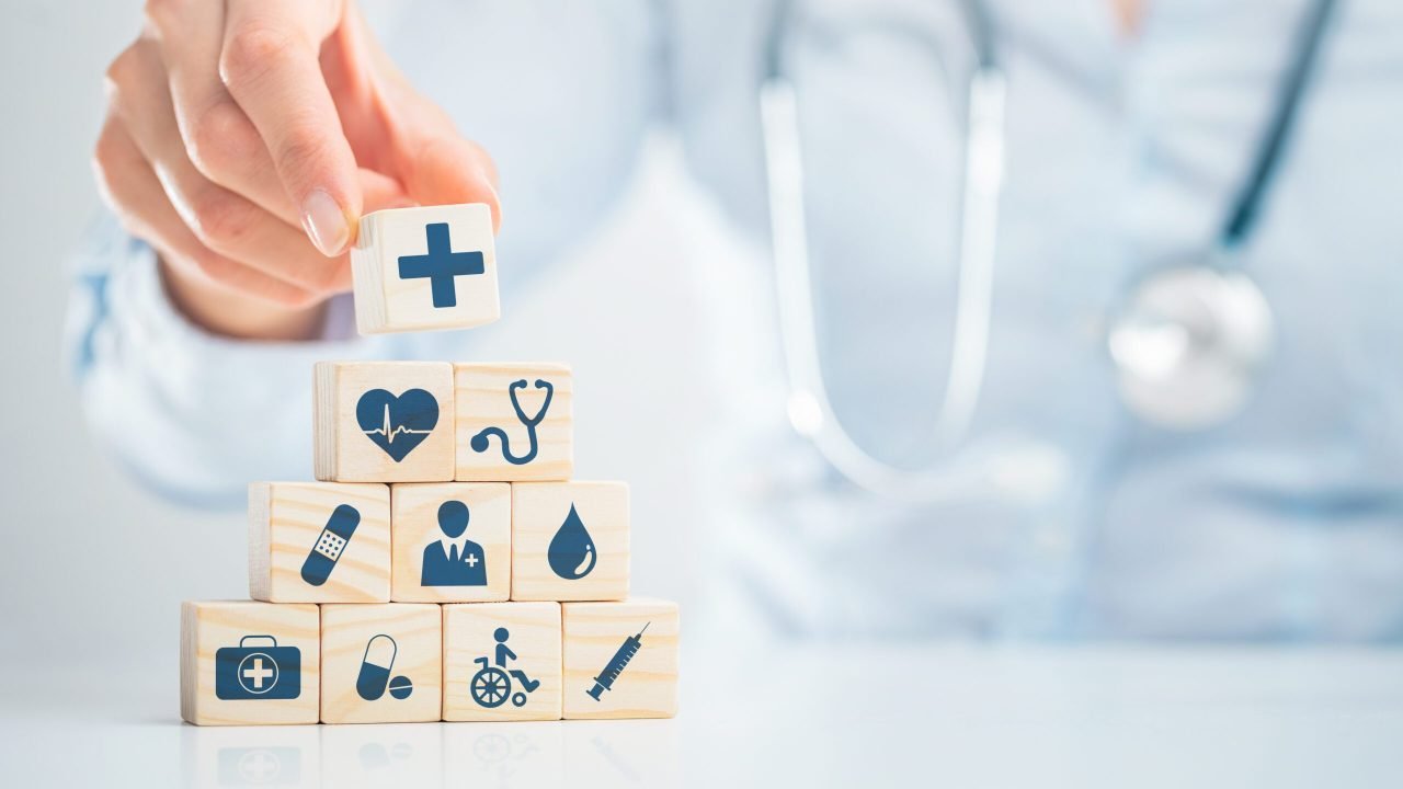 Hand arranging wood block with healthcare medical icon. Health insurance - concept.